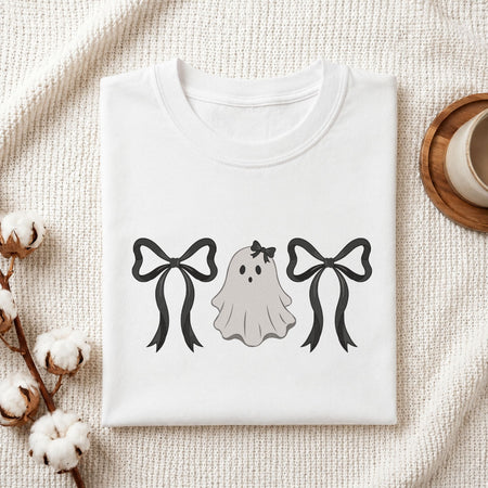  Folded white cotton t-shirt mockup featuring a cute ghost with bows machine embroidery design, styled with cotton stems and a wooden cup   