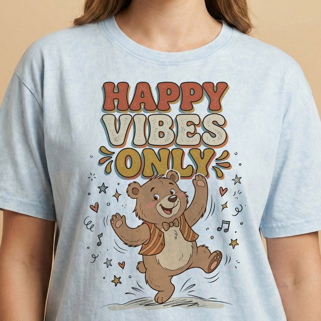 Light blue t-shirt with a bear graphic and 'Happy Vibes Only' text on a beige background