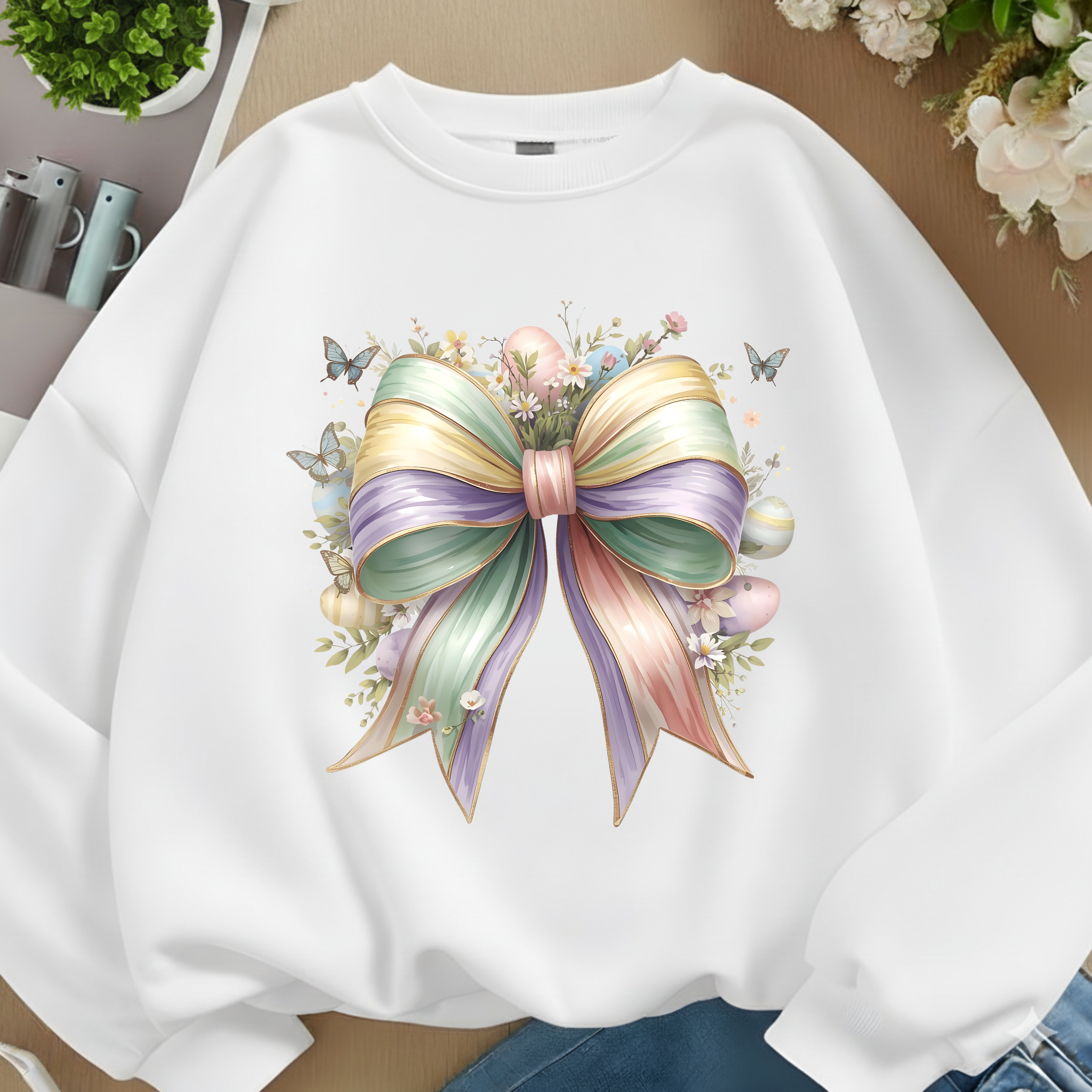 White sweatshirt with a colorful bow design on a neutral background