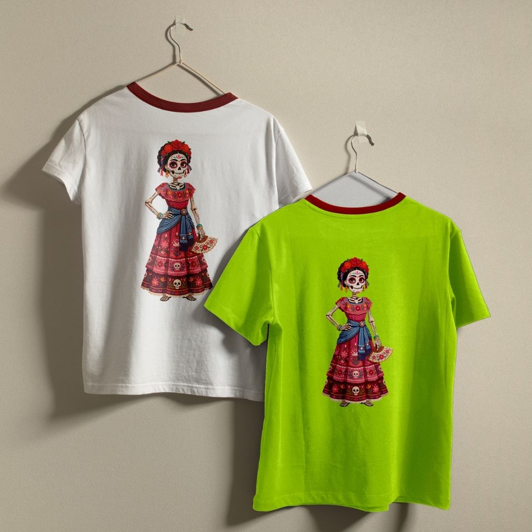 Two ringer t-shirts with red neck trims hanging on hangers against a beige wall. One shirt is white and the other is neon lime green, both featuring a colorful graphic of a Day of the Dead (Dia de los Muertos) woman on the back.