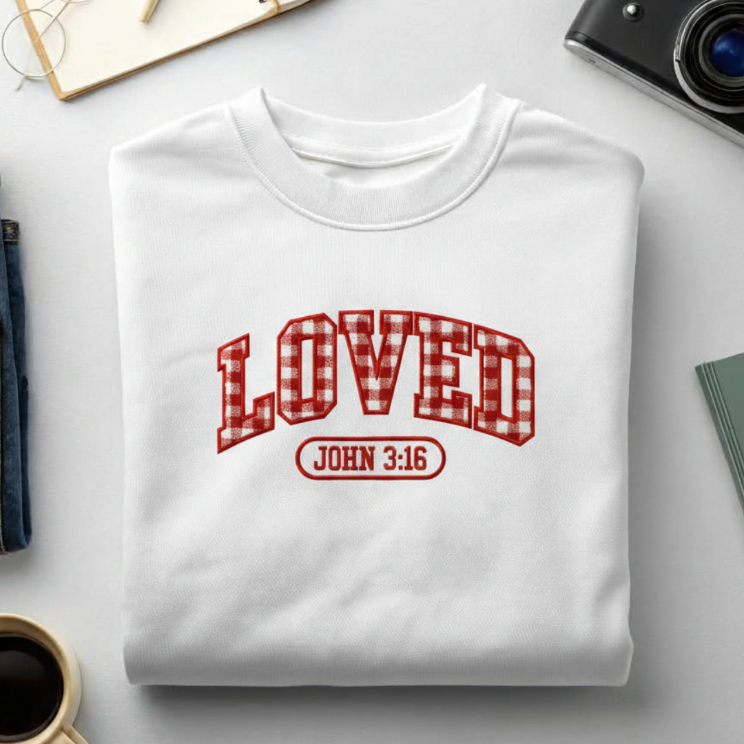 White sweatshirt with 'LOVED John 3:16' text on a light gray surface.