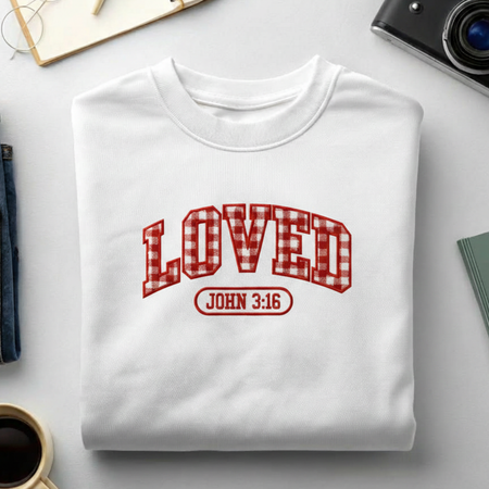 White sweatshirt with 'LOVED John 3:16' text on a light gray surface.