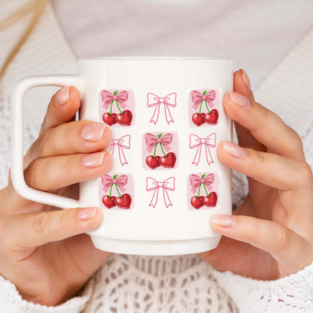 White mug with cherry and bow designs held by hands