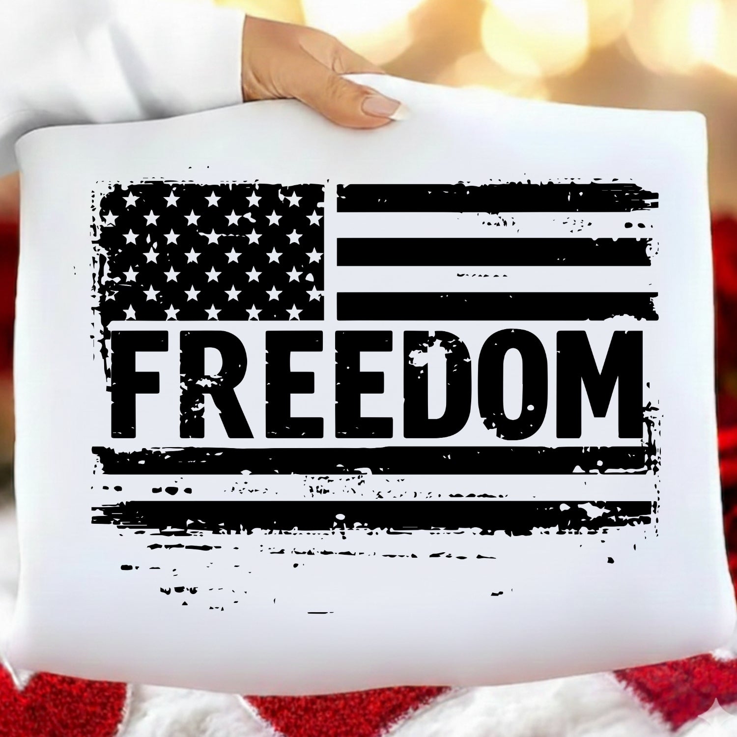 White pillow with American flag and 'FREEDOM' text held by a person against a blurred background