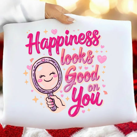 White pillow with 'Happiness looks good on you' text and a cartoon mirror held by a hand.