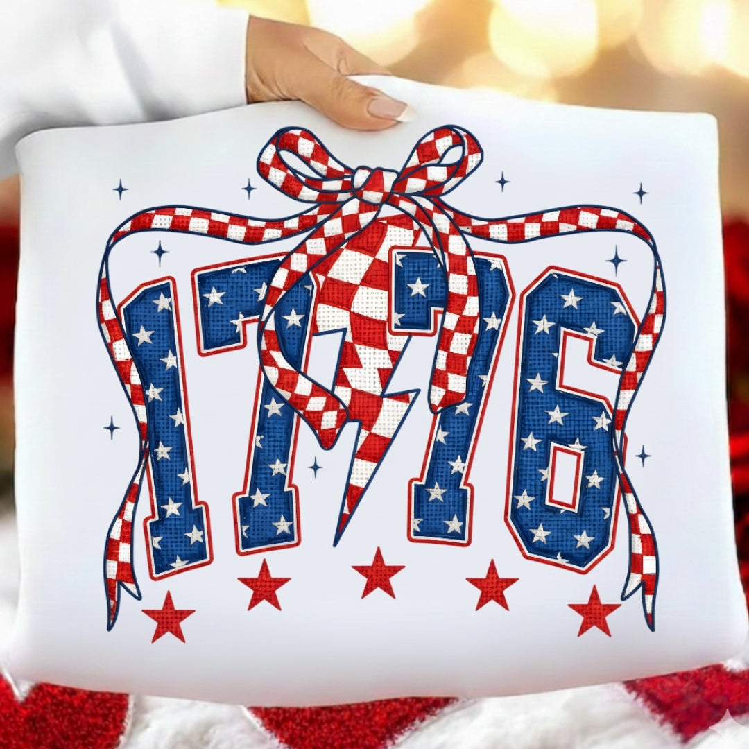 Decorative pillow with '176' design featuring stars and a bow, held by a hand.