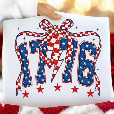 Decorative pillow with '176' design featuring stars and a bow, held by a hand.