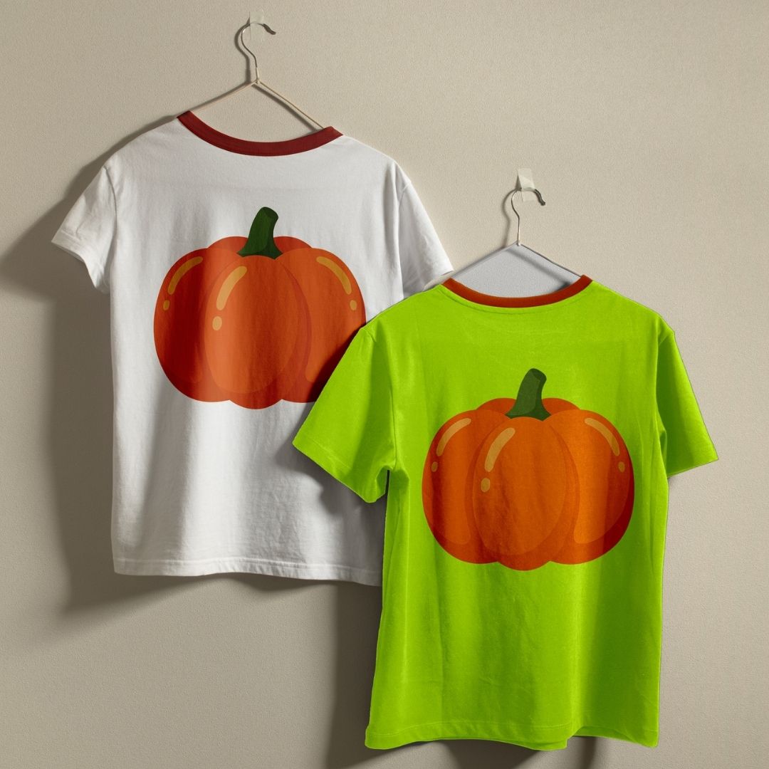 Two short-sleeve ringer T-shirts hanging on hangers against a plain beige wall. The left shirt is white with a red collar and features a large orange pumpkin graphic on the back.