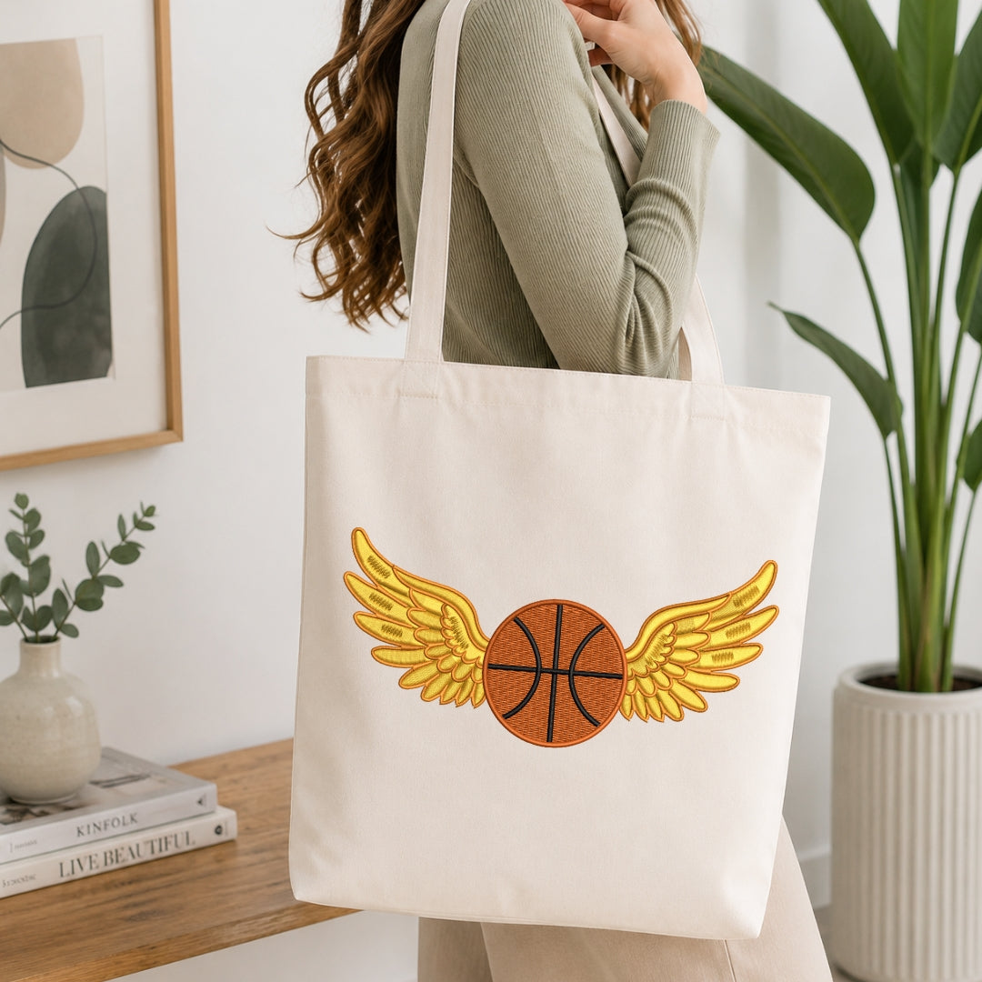 Person holding a tote bag with a basketball design featuring wings, in a home setting.