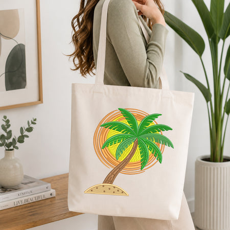 A woman wearing a sage green ribbed long-sleeve top carries a cream canvas tote bag with a colorful palm tree and sun graphic, set in a bright, modern room with a wooden table and potted plants.