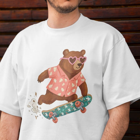 White t-shirt with a bear graphic wearing a pink shirt and sunglasses on a skateboard, against a wooden background.