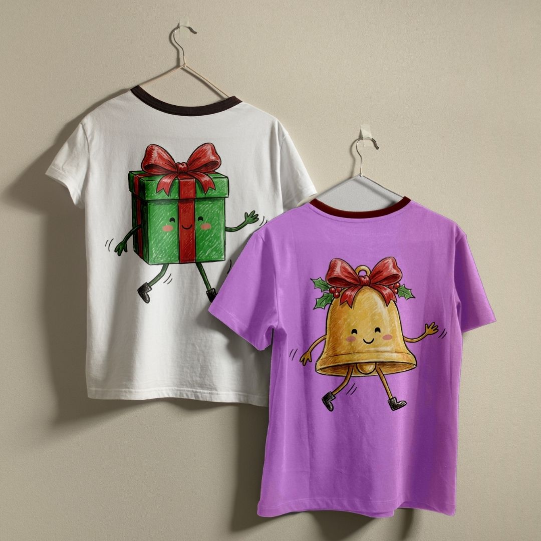 Two children's ringer t-shirts hanging on hangers against a plain beige wall. The left shirt is white with a dark red collar and features a cartoon green gift box graphic on the back.