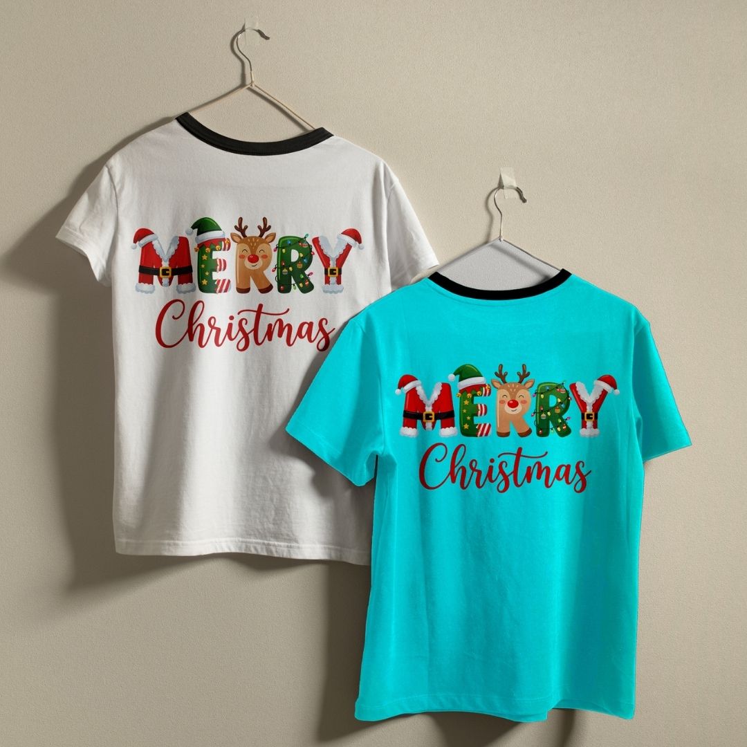 Two t-shirts hanging on a wall—one white and one turquoise—both showcasing the "MERRY Christmas" holiday print design.
