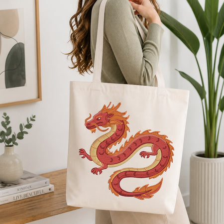 A person is shown carrying a cream-colored canvas tote bag that features the embroidered dragon design.