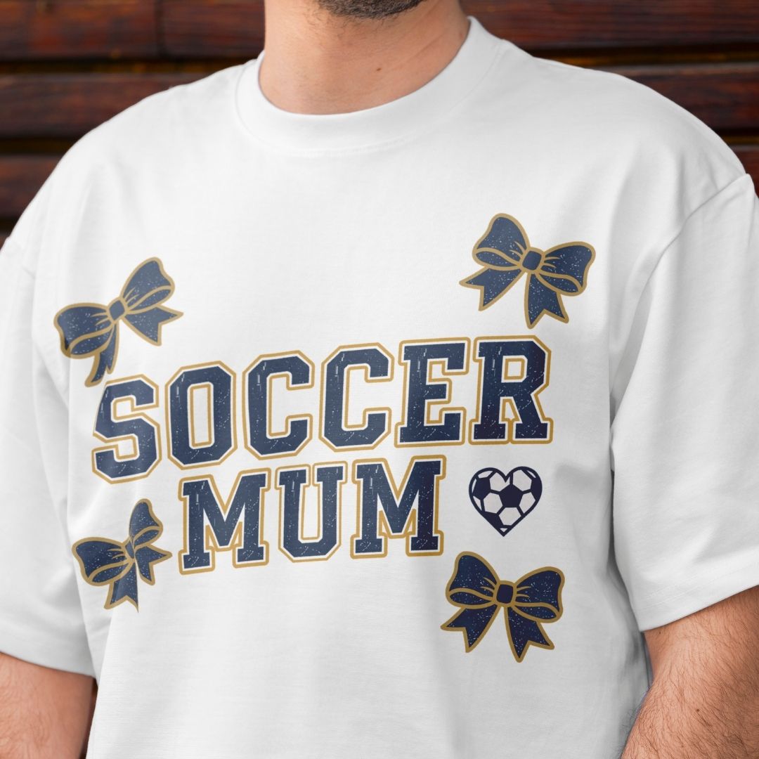 White t-shirt with 'Soccer Mum' text and decorative elements on a wooden background