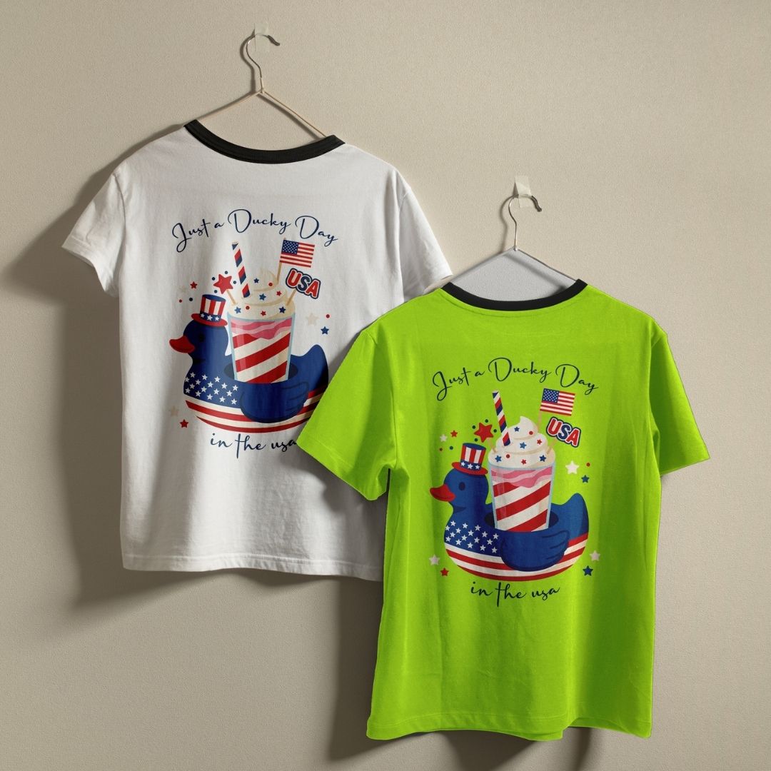 A white ringer t-shirt with a black collar and a solid purple t-shirt hanging on a wall, showcasing the custom 4th of July design.