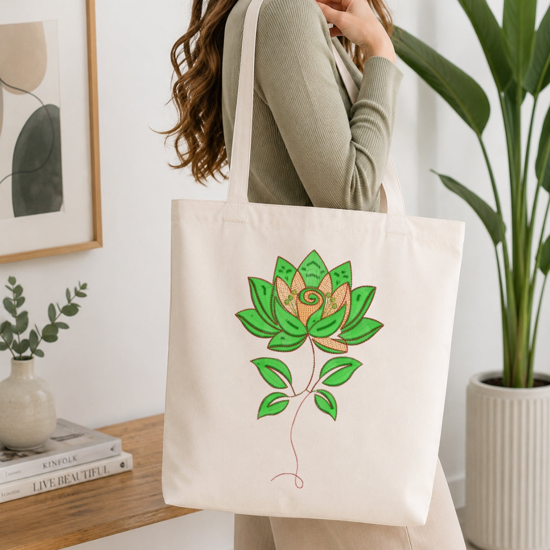 A woman wearing a sage green ribbed long-sleeve top carries a cream canvas tote bag with a green lotus flower illustration. The setting is a bright, modern room with a wooden table, books, a framed print, and a potted plant.