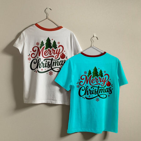 Two t-shirts hanging on a wall—one white and one bright blue—both displaying the "Merry Christmas" holiday graphic print.