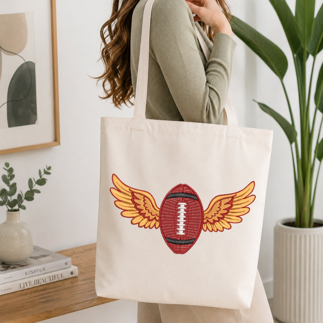 Person holding a tote bag with a football design featuring wings in a home setting.