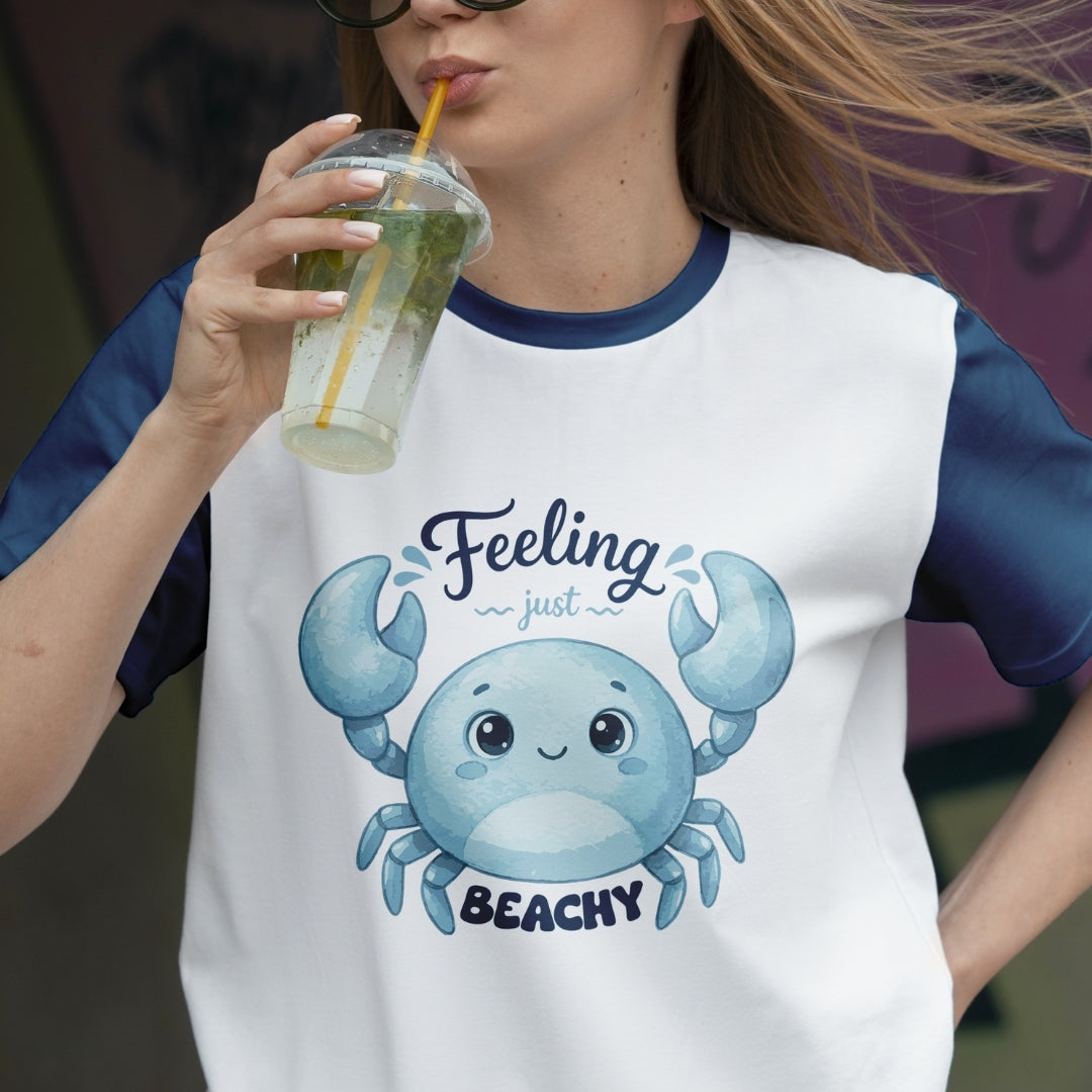 Person wearing a t-shirt with a cartoon crab and text, holding a drink.