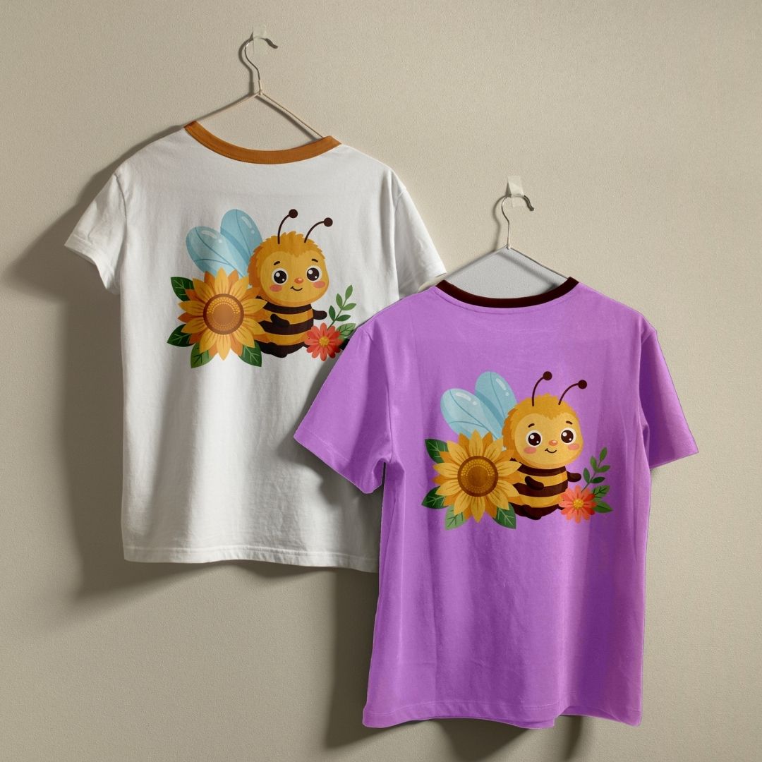 Two children's short-sleeve ringer t-shirts hanging on hangers against a plain beige wall. The left shirt is white with a brown collar trim and features a cartoon bee, sunflower, and flower graphic on the back.