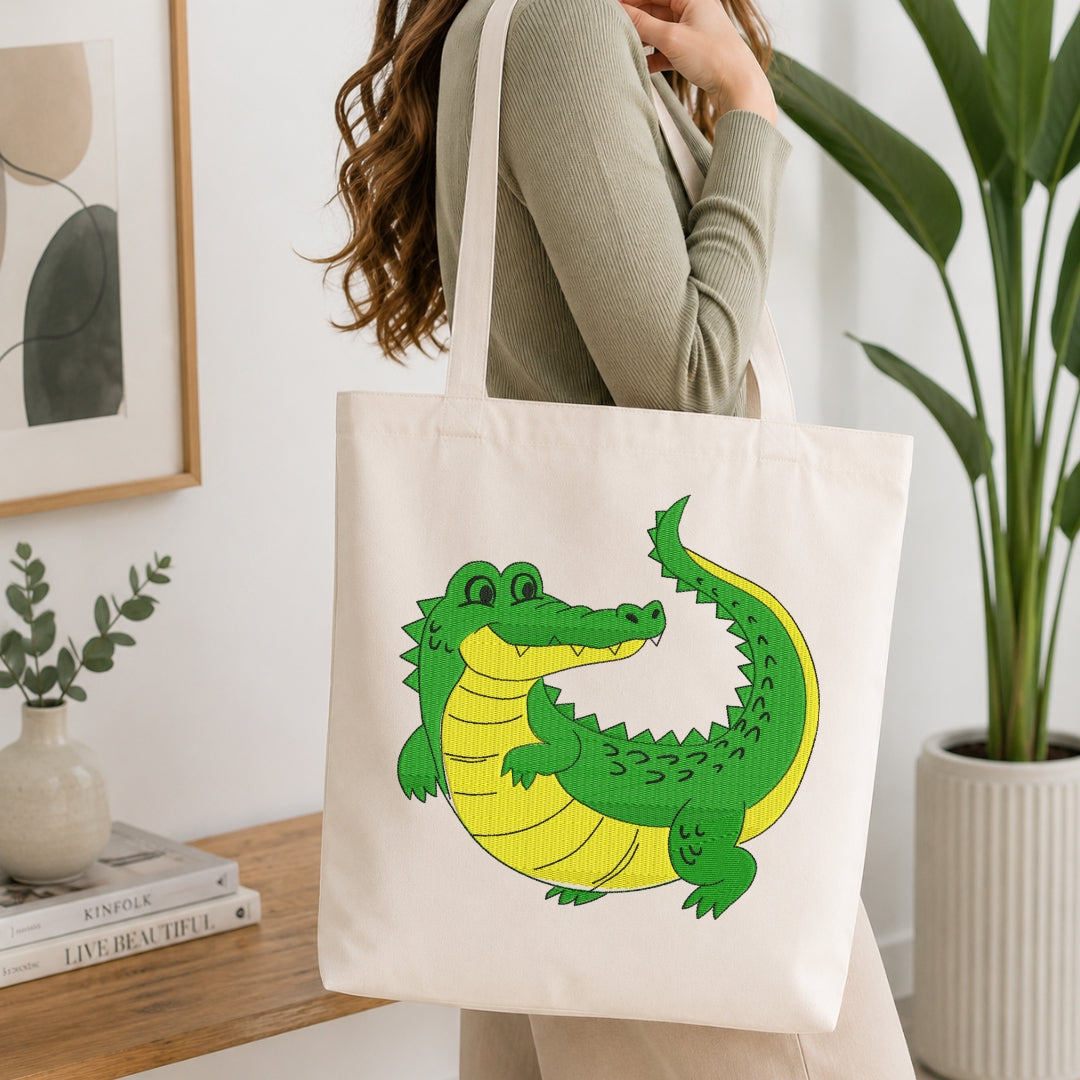 A woman carries a cream canvas tote bag featuring a colorful cartoon alligator design in green and yellow, set against a bright, modern indoor background with a wooden table and potted plants.
