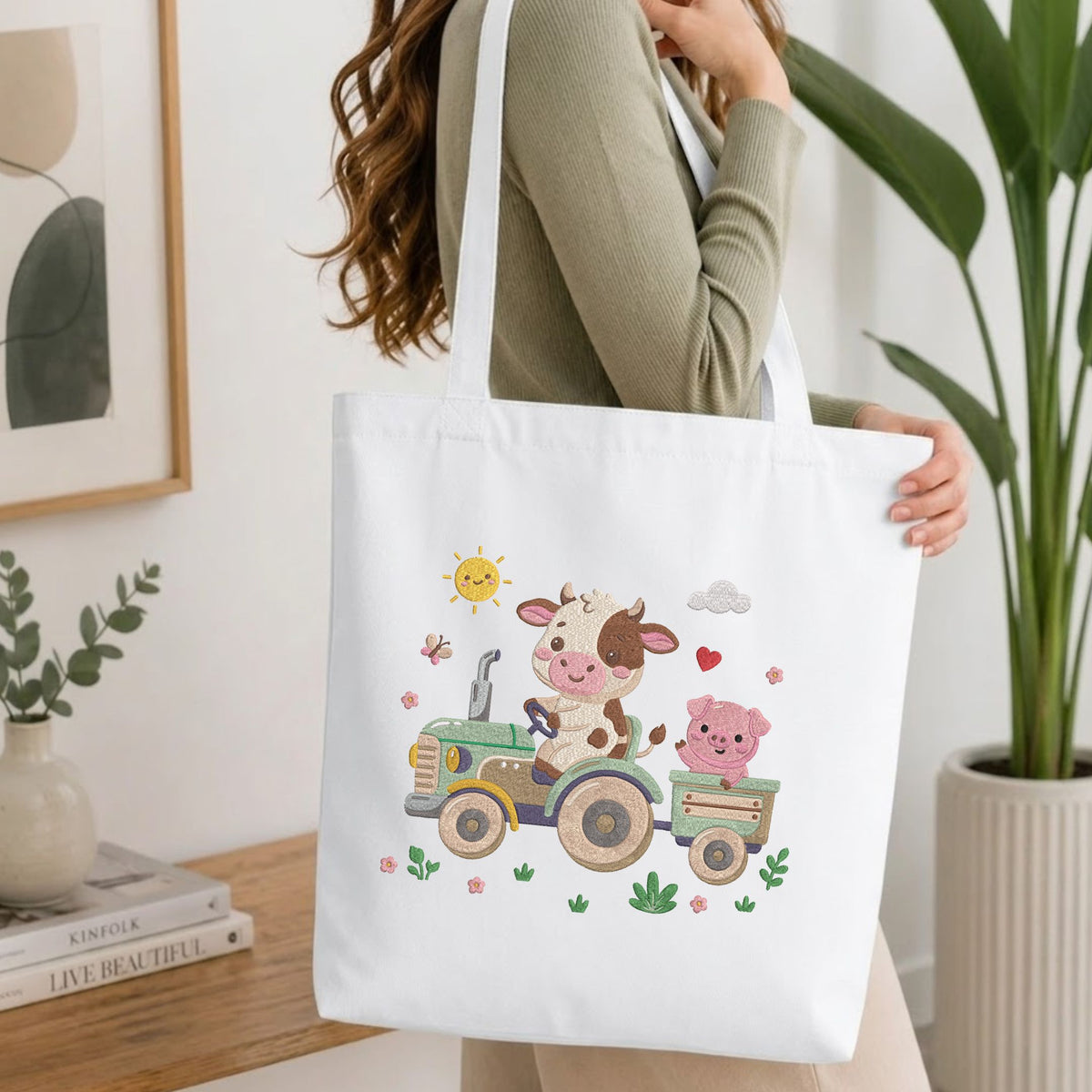 Woman carrying a white natural canvas tote bag featuring an embroidered farm animals design in a bright, modern interior setting