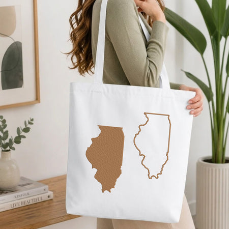 Woman carrying a white natural canvas tote bag featuring an embroidered Georgia state map design in a bright, modern interior setting.   