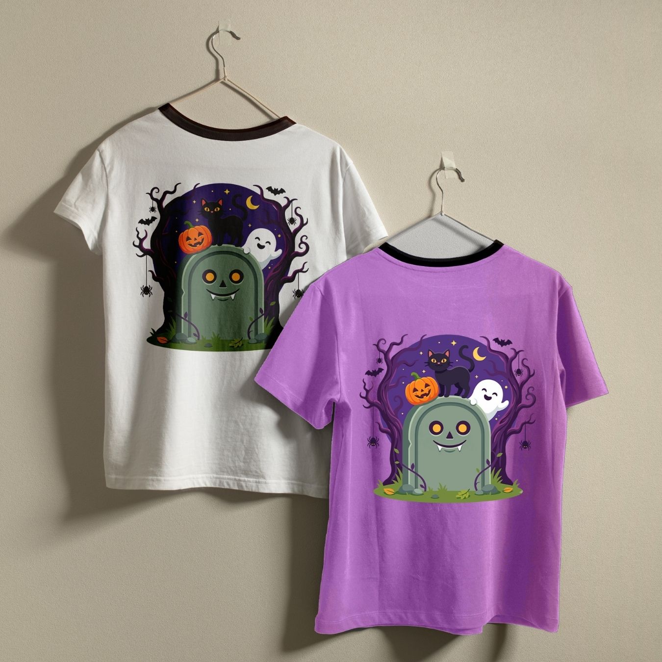 Two children's ringer t-shirts hanging on hangers against a beige wall. One shirt is white with a black collar and features a Halloween graphic on the front showing a green tombstone, orange jack-o'-lantern, white ghosts, and a purple spooky background.
