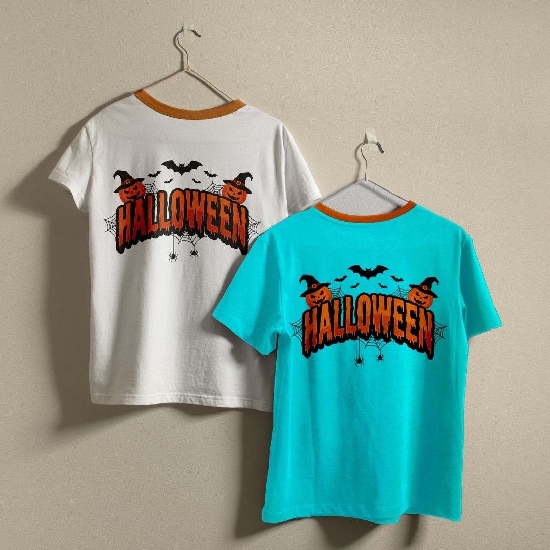 Two t-shirts hanging on a wall—one white and one bright blue—both displaying the "Halloween" holiday graphic print.