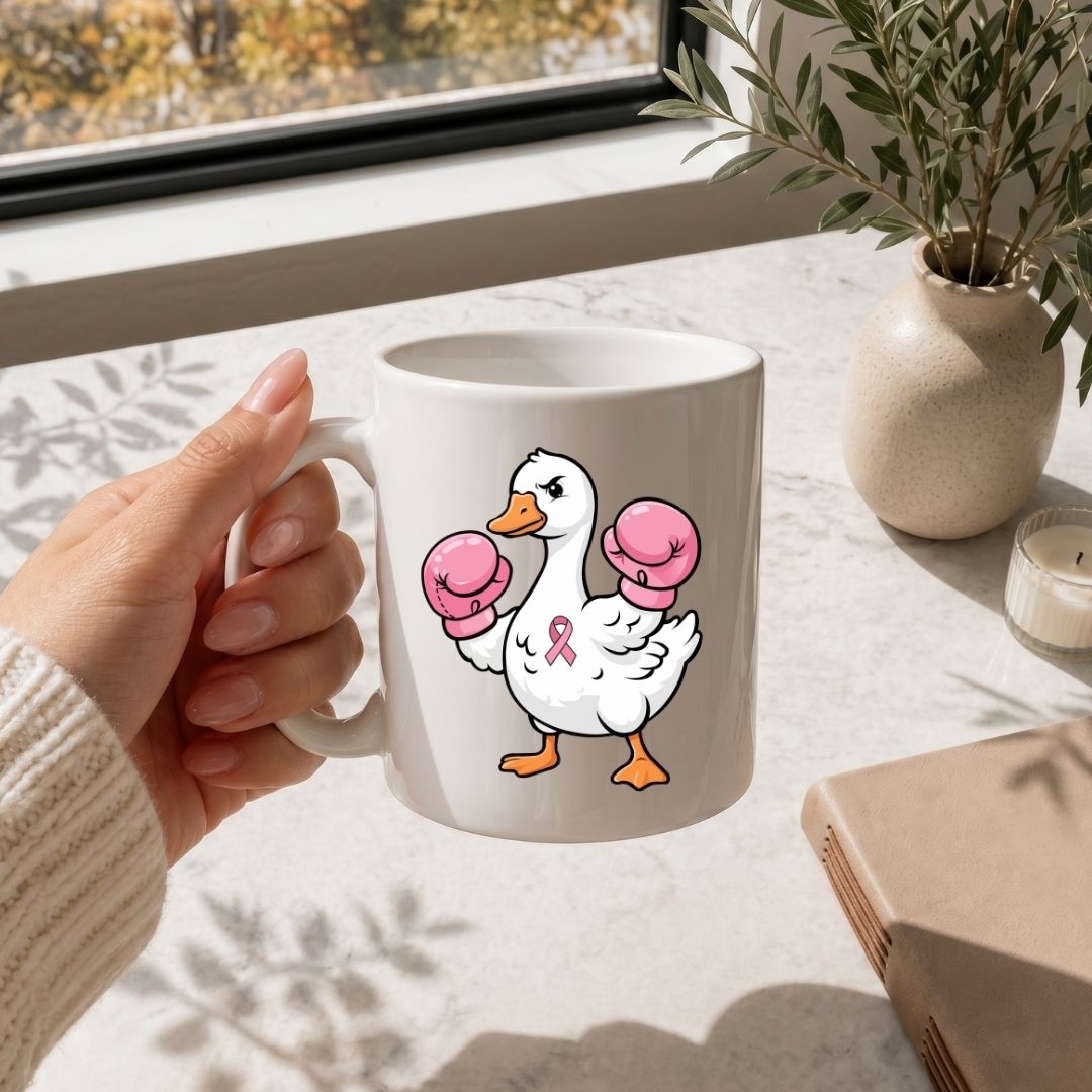 A tall white stainless steel tumbler mockup with a black straw, printed with the boxing duck breast cancer design, set outdoors on a wooden table near greenery.