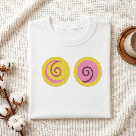 A folded white t-shirt with two circular graphic prints on the front, styled on a textured cream knit blanket with cotton bolls and a wooden cup in the background.