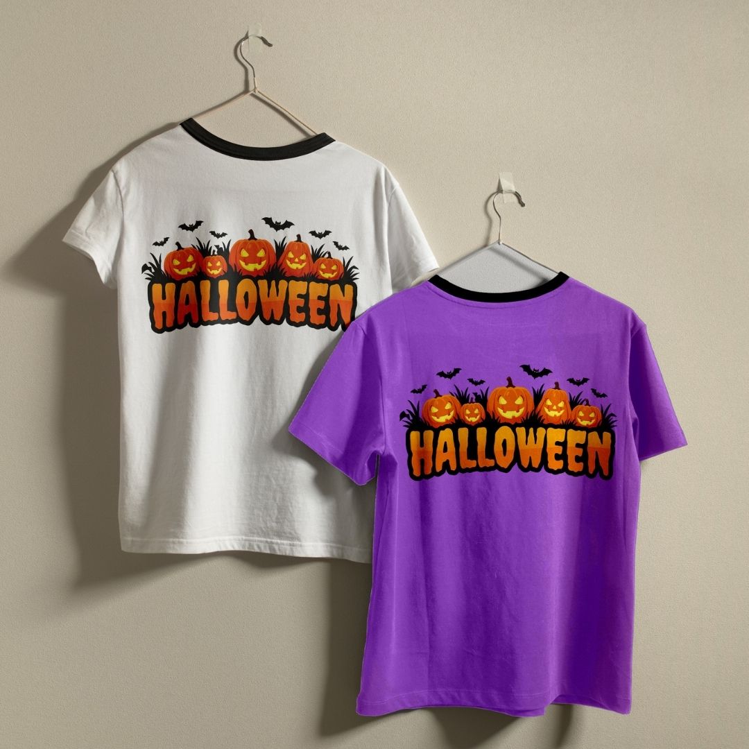 Two t-shirts hanging on a wall—one white and one purple—both featuring the Halloween pumpkin patch back print design.