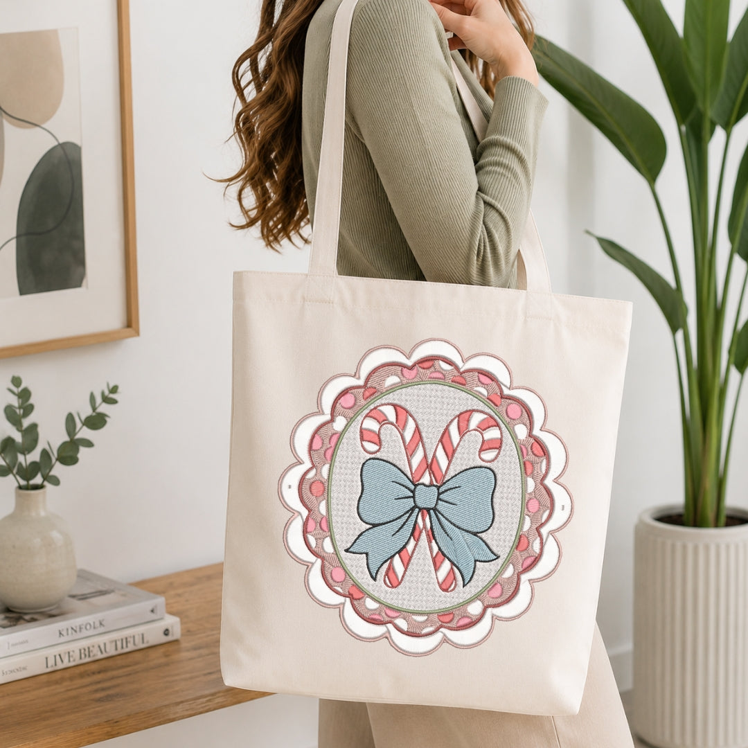 A woman wearing a sage green ribbed sweater carries a cream canvas tote bag with a scalloped circular holiday design featuring candy canes and a blue bow.