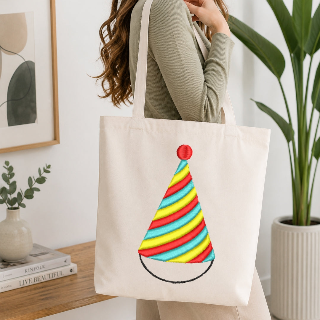 A person carrying a canvas tote bag decorated with the same party hat embroidery design.