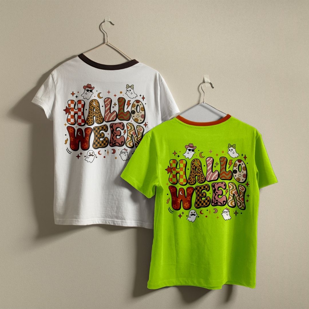 Two kids' Halloween-themed t-shirts hanging on hangers against a plain beige wall. One shirt is white with a black collar trim and a colorful 'HALLOWEEN' graphic on the back.
