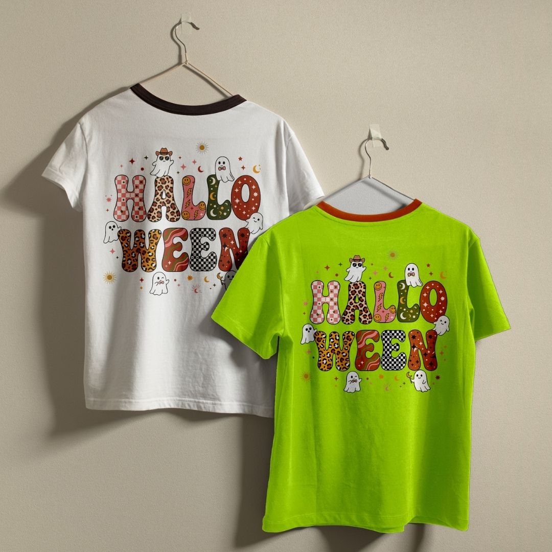 Two children's Halloween-themed short-sleeve t-shirts hanging on hangers against a plain beige wall. The left shirt is white with a dark brown collar and features a colorful 'HALLOWEEN' graphic on the back with a cowboy, ghosts, and spooky details.