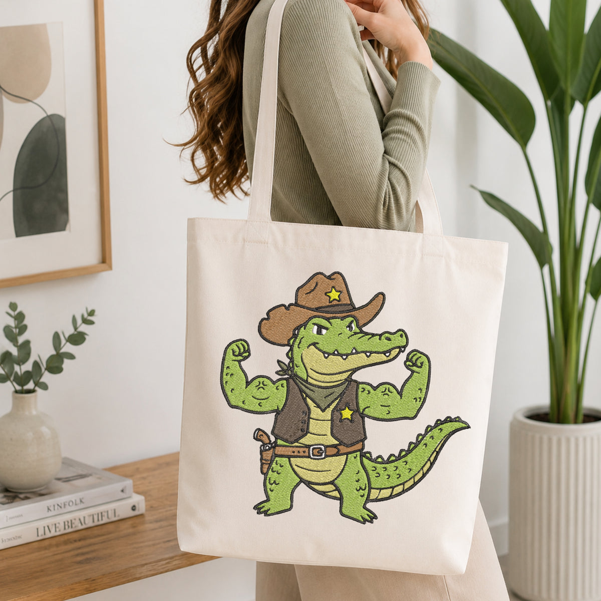 Person holding a white canvas tote bag styled with a cowboy alligator embroidery patch design.