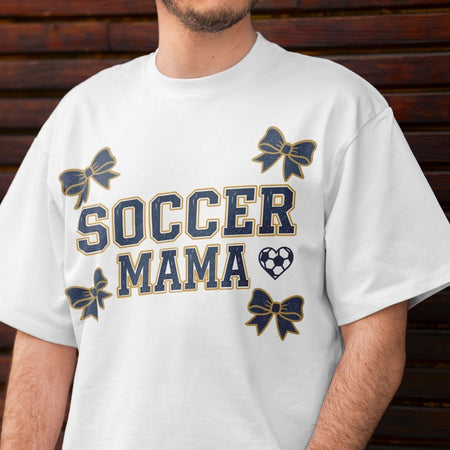White t-shirt with 'Soccer Mama' text and graphics on a wooden background