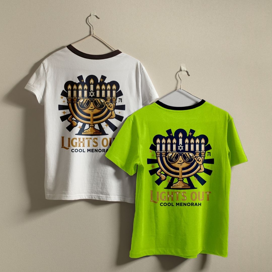 A hand holding a white ceramic mug printed with a funny graphic of a golden menorah wearing sunglasses and the text "LIGHTS OUT COOL MENORAH".