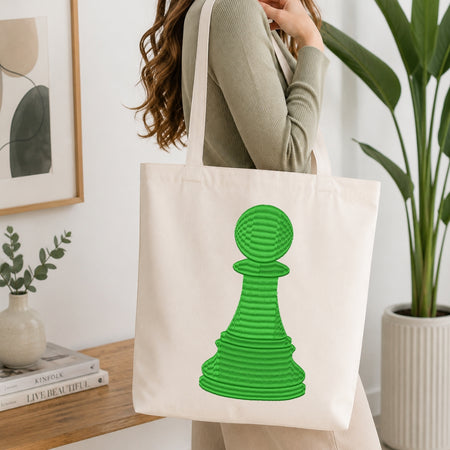 A person carrying a canvas tote bag decorated with the embroidered green chess pawn design.