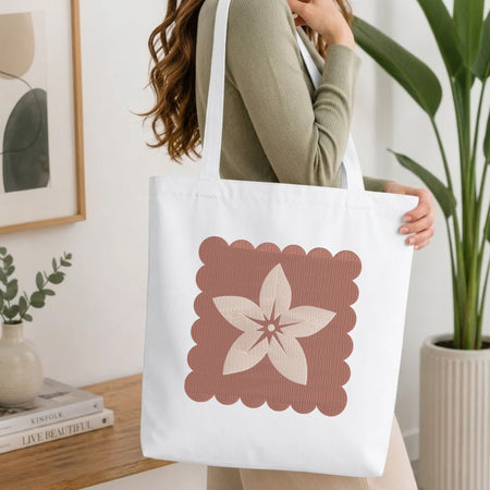 Woman carrying a white natural canvas tote bag featuring an embroidered minimal flower design in a bright, modern interior setting.   