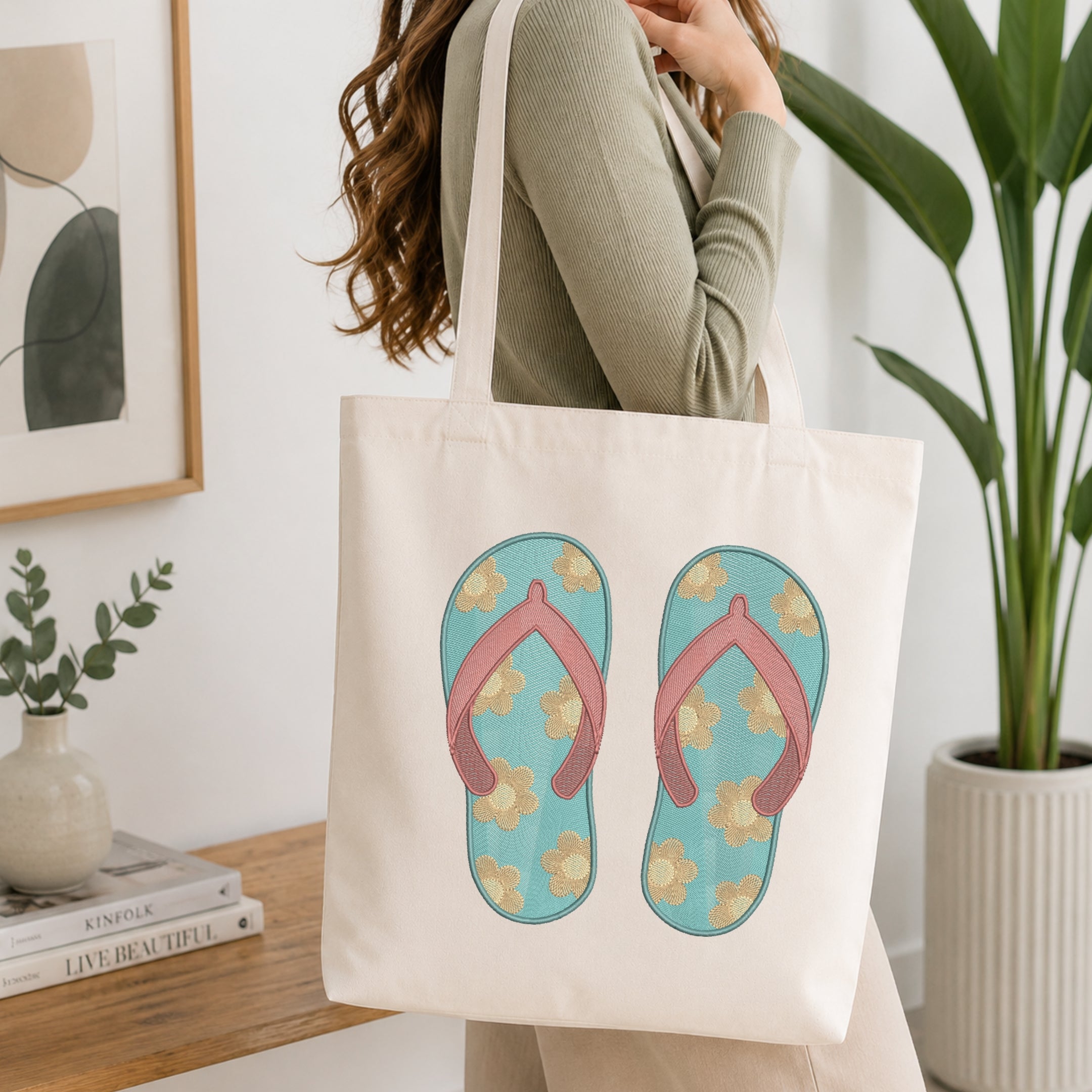 A woman wearing a sage green ribbed long-sleeve top carries a cream canvas tote bag. The bag features a graphic print of a pair of light blue flip-flops with pink straps and yellow floral details.