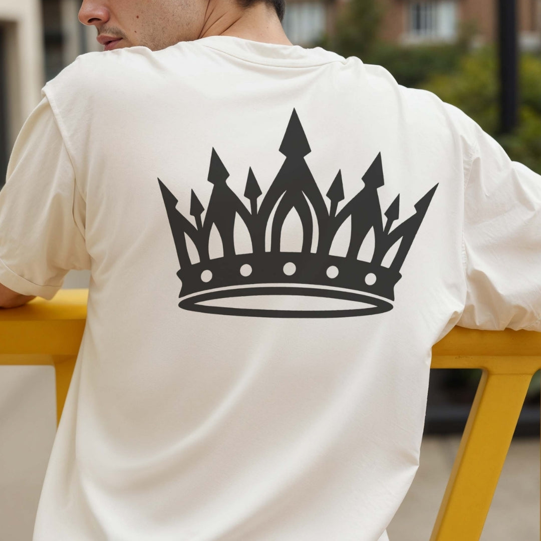 Person wearing a white t-shirt with a black crown design on the back, sitting outdoors.