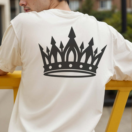Person wearing a white t-shirt with a black crown design on the back, sitting outdoors.