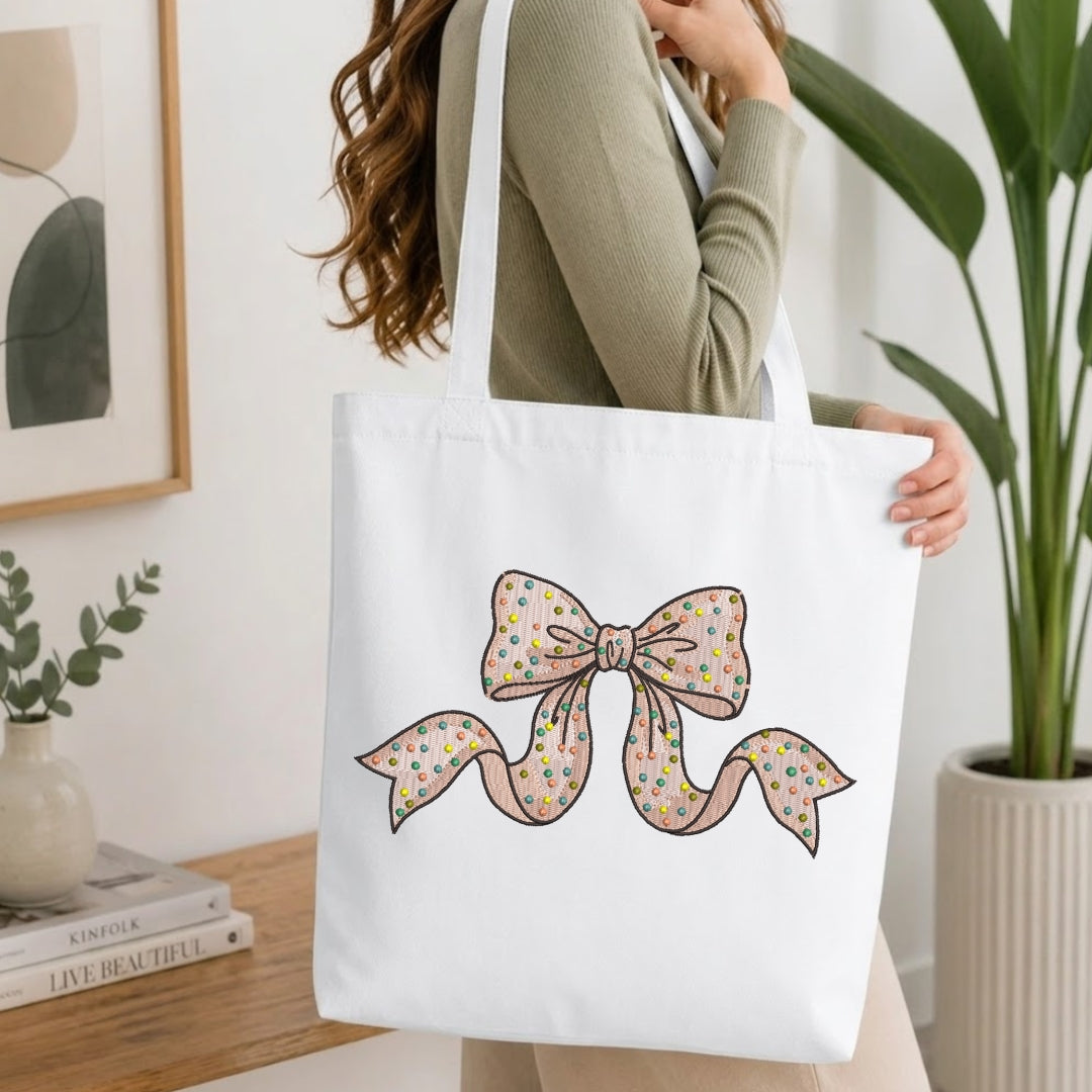 Polka dot bow embroidery stitched onto a folded white t-shirt.