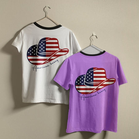 A white ringer t-shirt with a black collar and a solid purple t-shirt hanging on a wall, showcasing the custom country music design asset print.