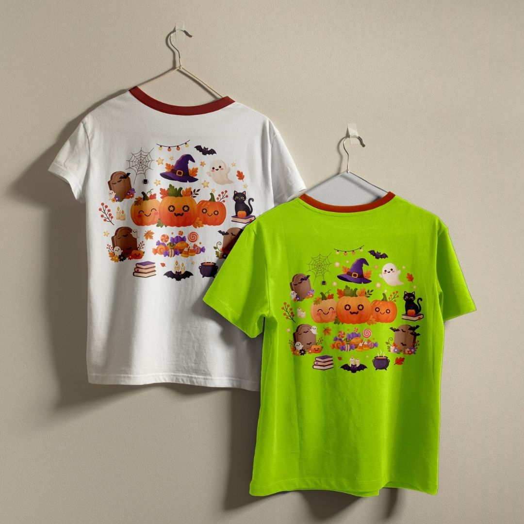 Two children's short-sleeve ringer T-shirts hanging on hangers against a plain beige wall. The left shirt is white with a red collar trim and a colorful Halloween graphic on the back featuring pumpkins, ghosts, bats, and witches.