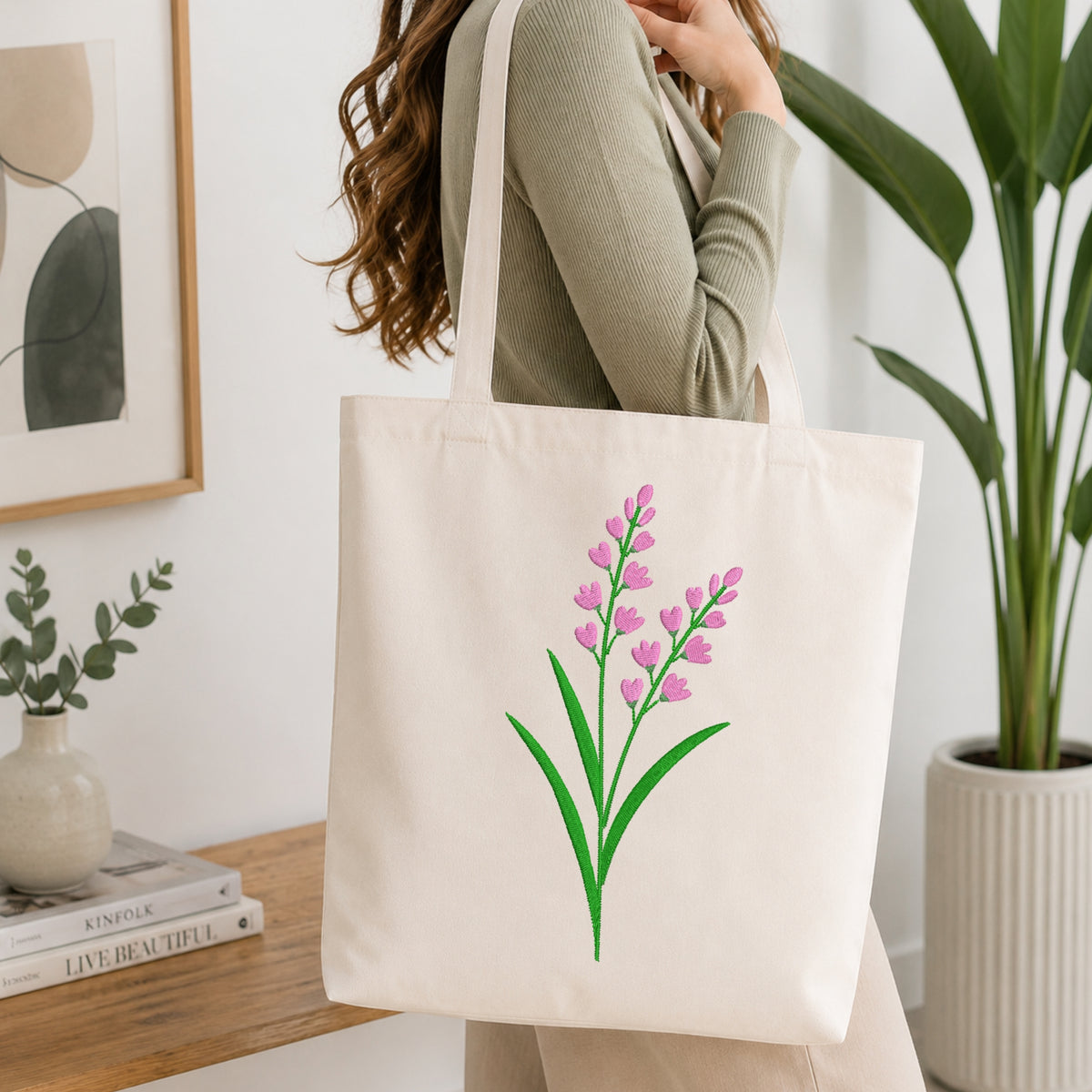 Woman carrying a beige canvas tote bag styled with a pink lavender embroidery pattern.