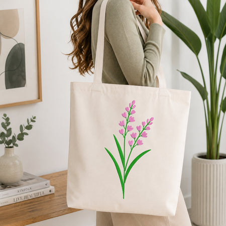 Woman carrying a beige canvas tote bag styled with a pink lavender embroidery pattern.